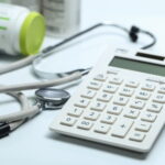 Calculadora, estetoscópio e frascos de remédio, simbolizando os custos e reajustes de plano de saúde.
